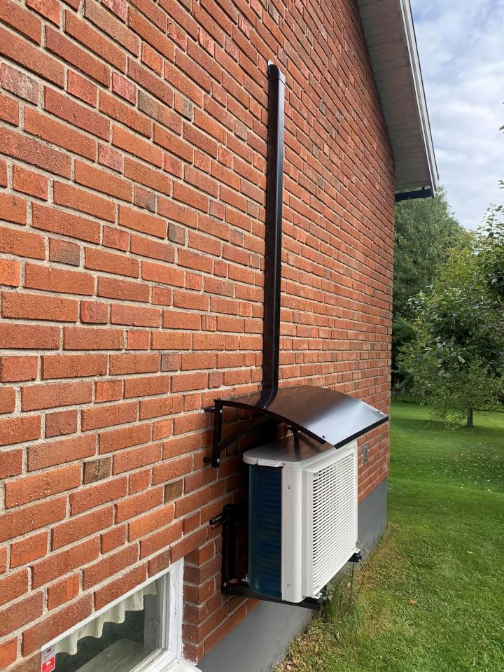 Utedel till luftvärmepump monterad på husvägg med skyddstak